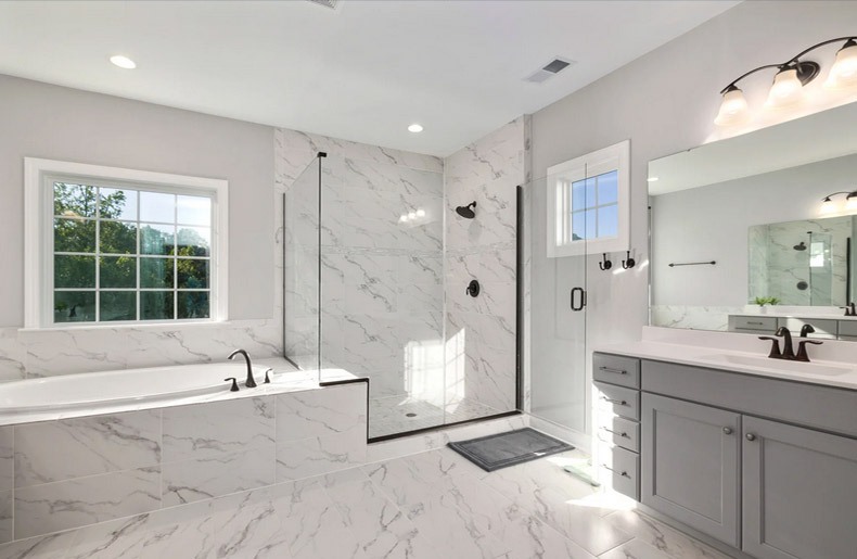 Bright bathroom featuring marble tiles and a bathtub.